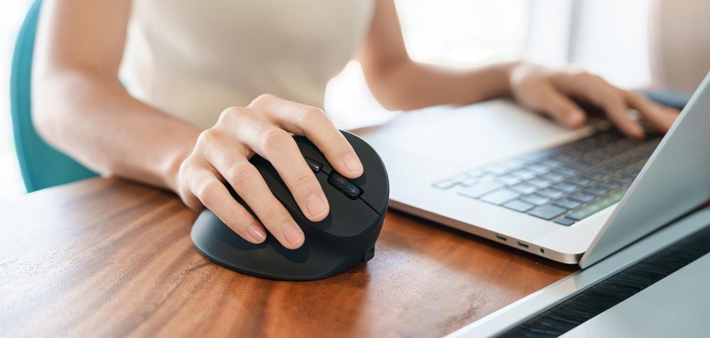 Woman using ergonomic mouse with laptop